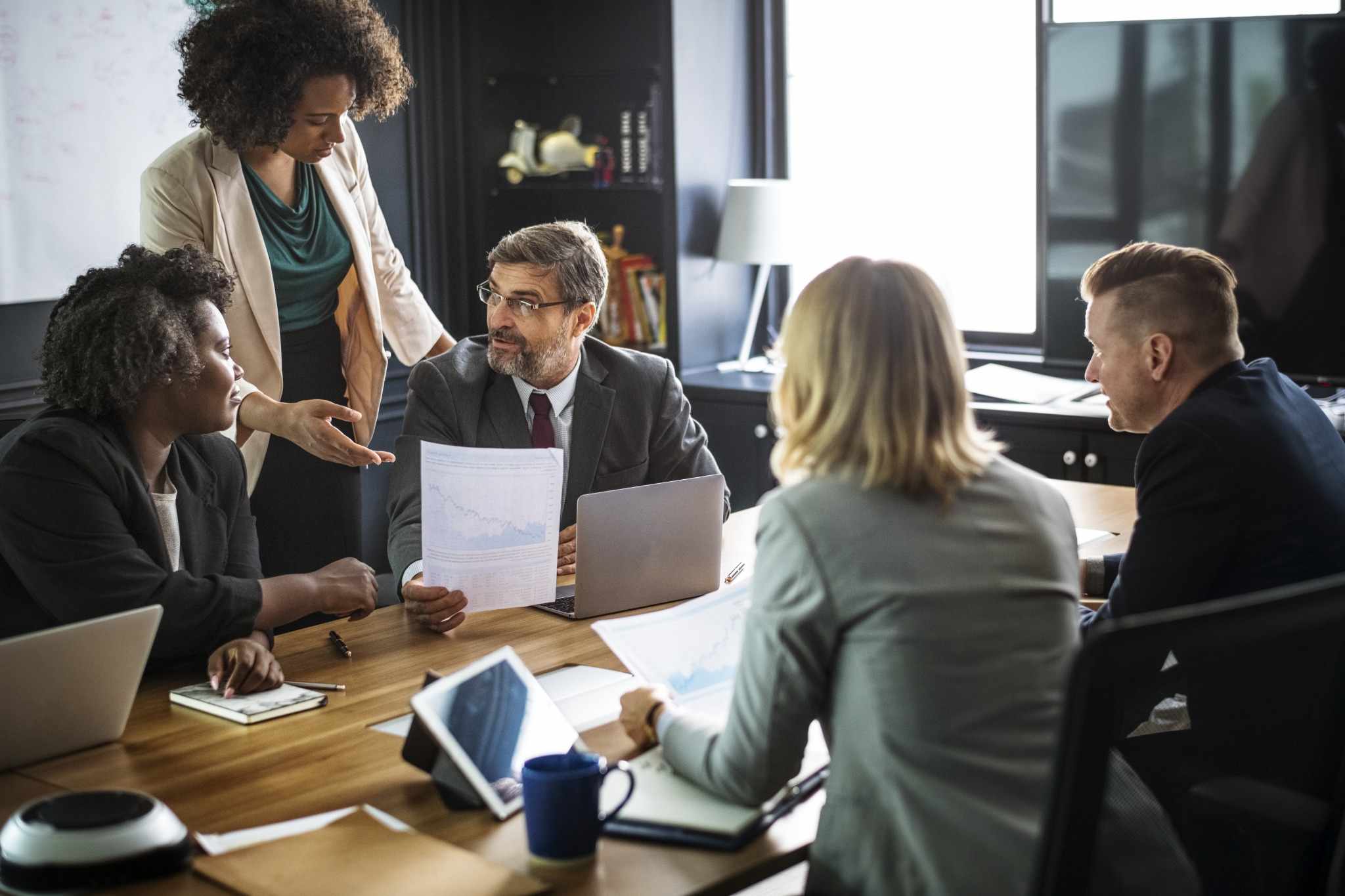 A team around a meeting table going through printed documents and a laptop together.