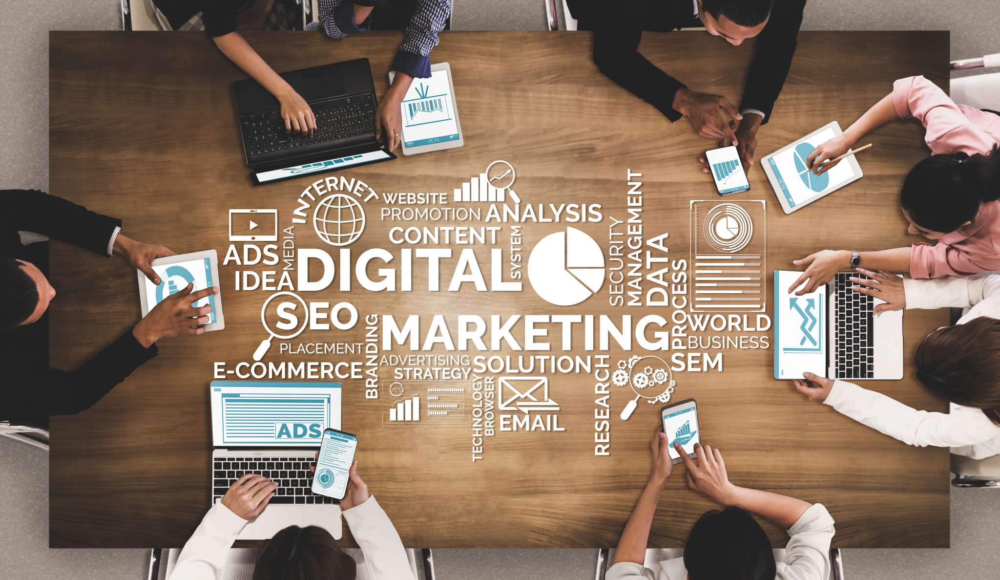 A meeting table seen from above, with laptops, tablets and a digital marketing diagram between them.